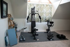 Person performing controlled bodyweight squats beside a workout mat in a bright home space.