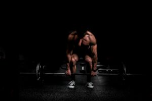 Adults performing controlled resistance exercises in a bright, well-ventilated gym with weights and water nearby.