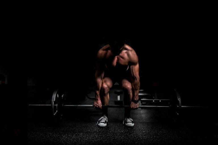 Adults performing controlled resistance exercises in a bright, well-ventilated gym with weights and water nearby.